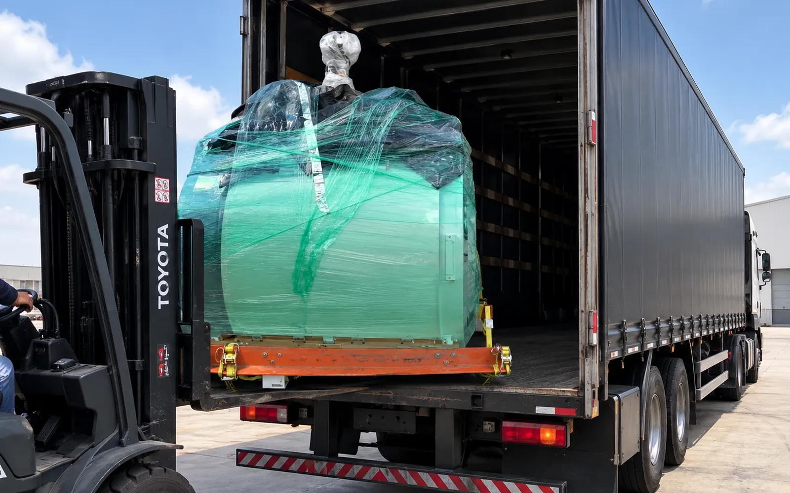 Empilhadeira carregando uma máquina embalada em um caminhão baú